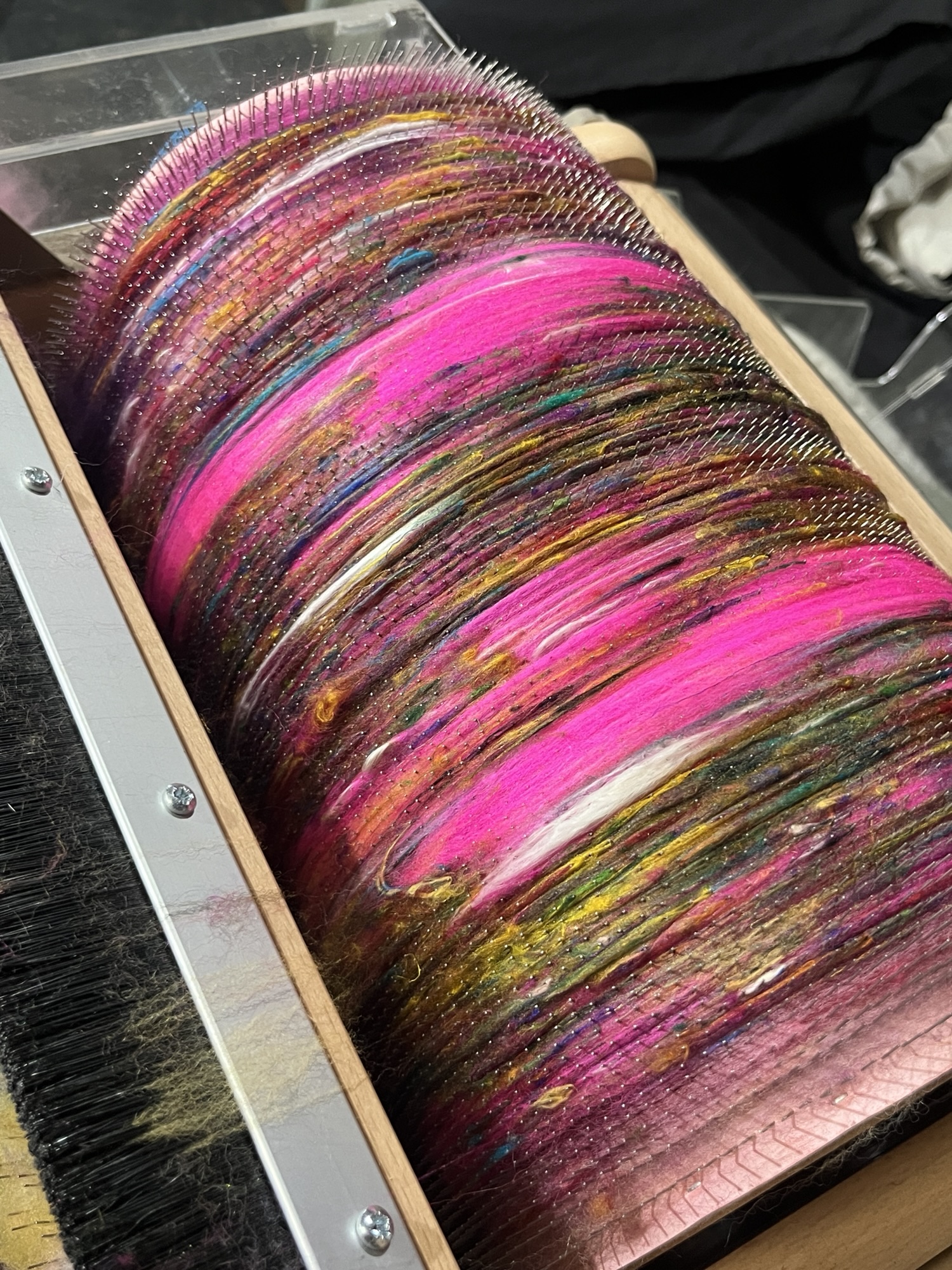 Handspun wool batt for spinning or felting: bright pink NZ wool blended with silk and kid mohair, featuring yellow and white accents, being blended on an Ashford drum carder